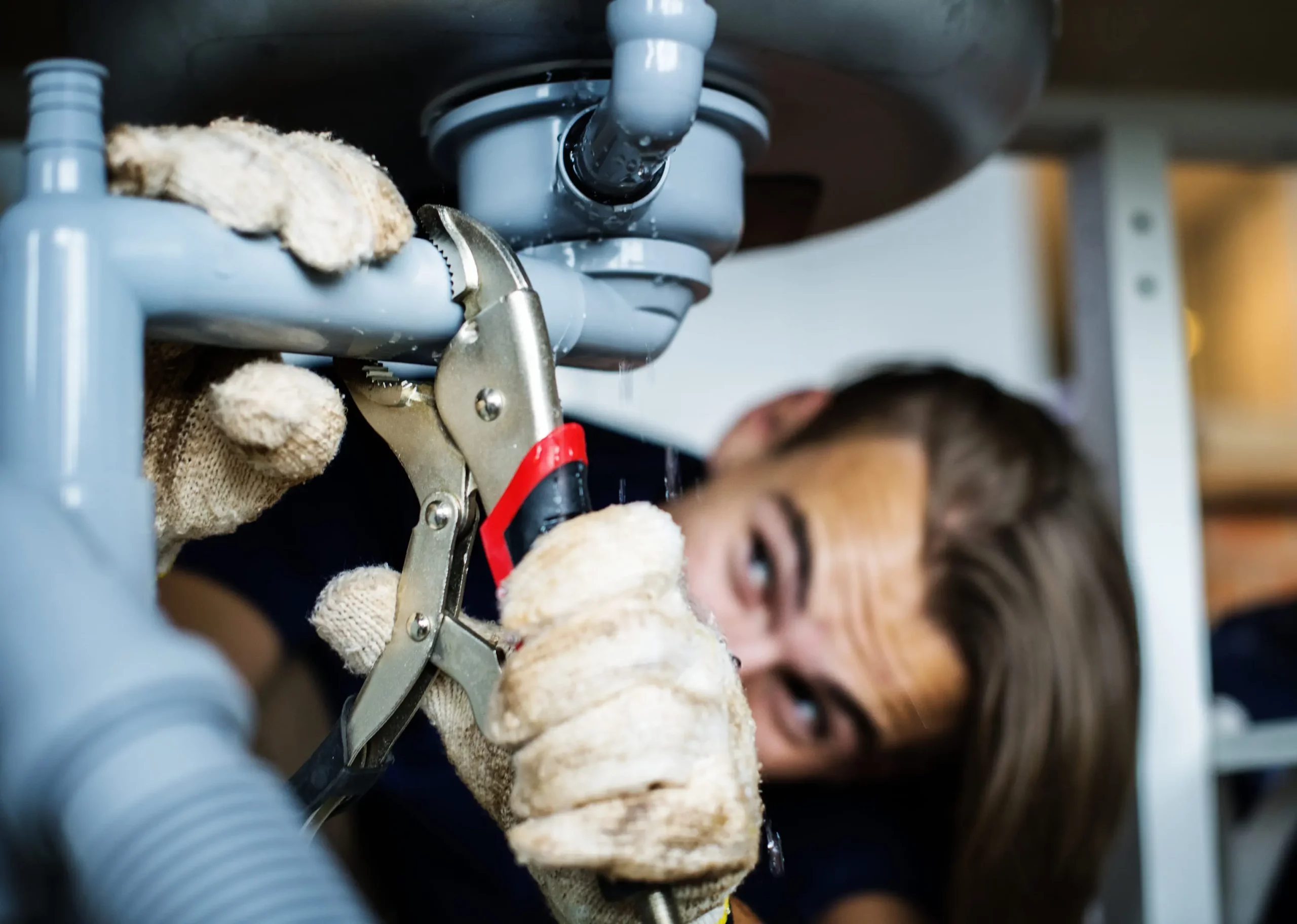 Fontanero de empresa de reformas y servicios integrales en Guadalajara reparando tubería bajo fregadero